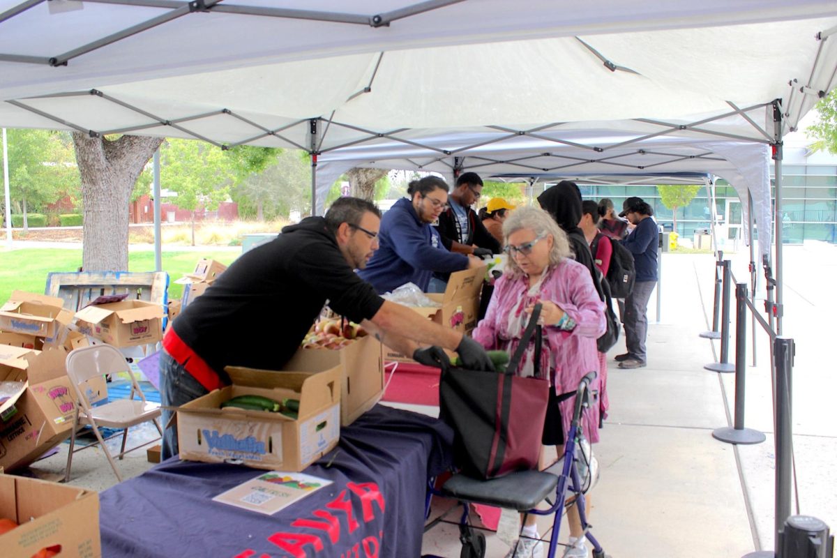 ARC Produce Pantry employee serves a zucchini to a student on Oct. 16. (Photo by Jose Leon)