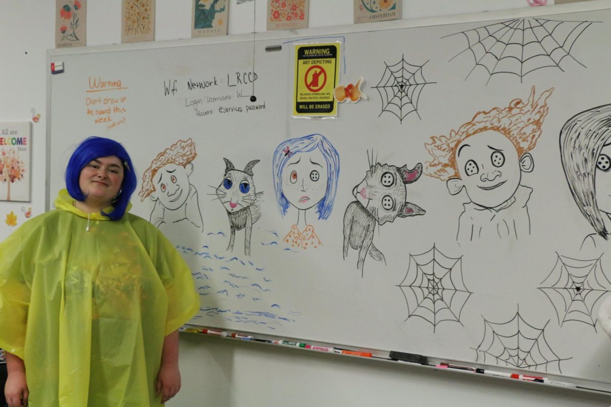 Peer mentor Laci Fugler, costumed as Coraline alongside her drawings of Coraline and others (Photo by Jose Herrera) 