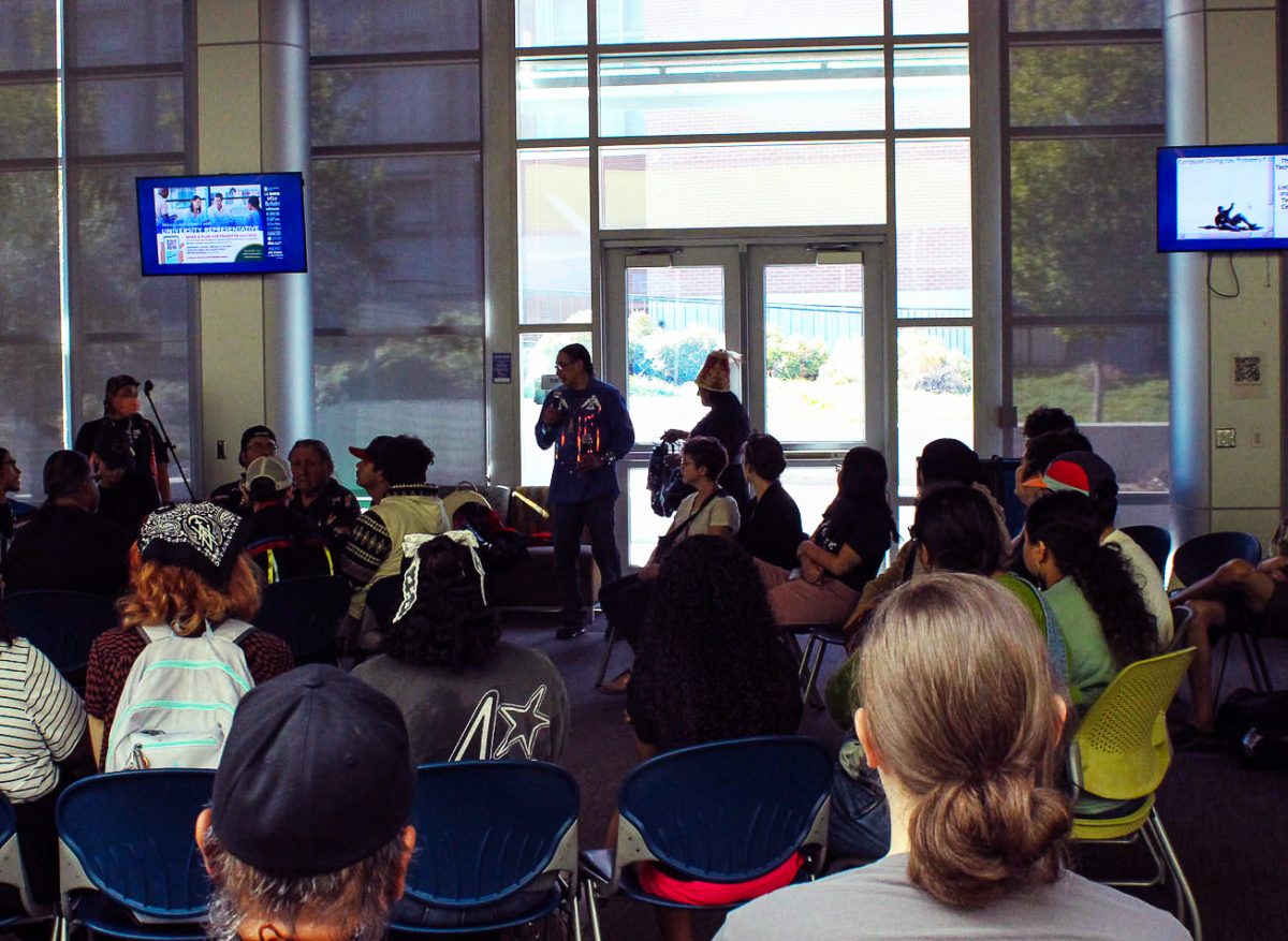 Jesus Valle, director of the Native American Resource Center, holds the microphone and addresses the audience in the American River College Student Center for Indigenous People's Day on Oct. 14. (Photo by Abigail Harless)